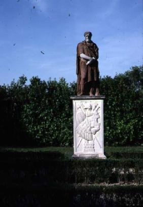 View of the garden detail of travertine sculpture of a male figure on a marble base decorated with a