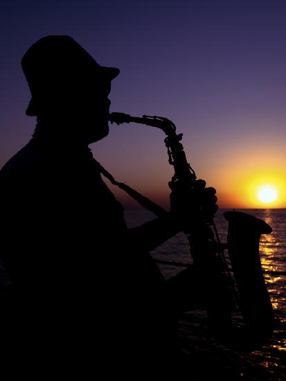 a musician playing the saxophone at sunset