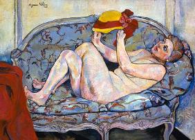 Lying female act on a chaise longue with hat in th