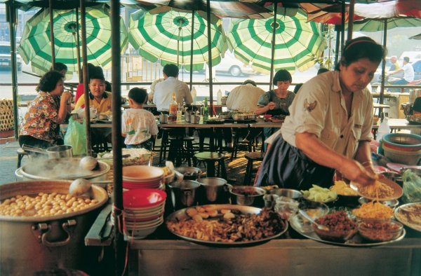 Cook preparing meals and sun-umbrellas hanging like large flowers in background (photo)  de 