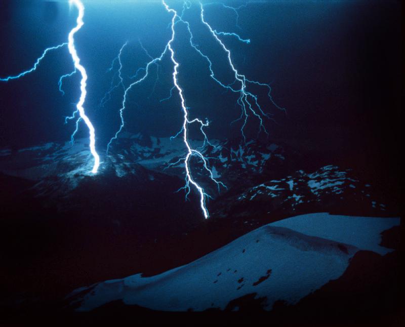 Lightning during a storm over snowy mountains de 