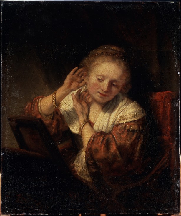 Young Woman trying on Earrings de Rembrandt van Rijn