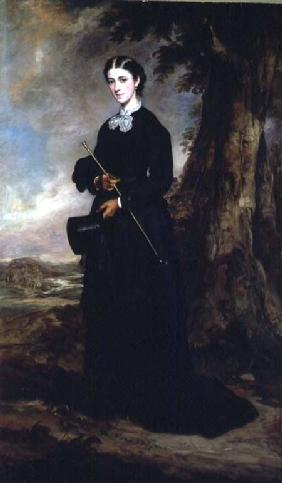 Young woman wearing a black riding habit and standing in a landscape